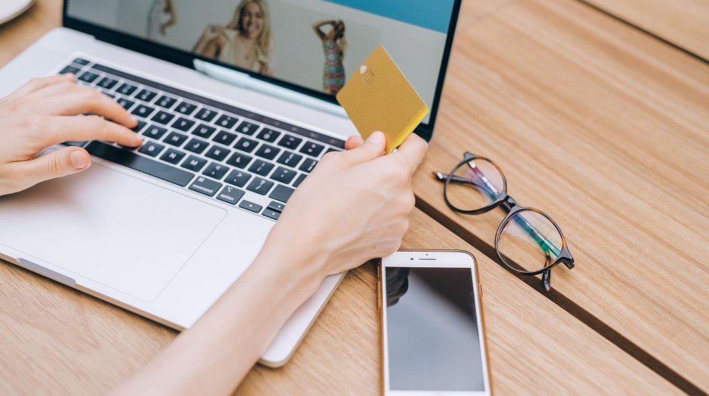 Pessoa fazendo uma compra online com cartão de crédito e smartphone
