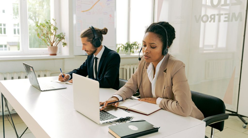 Equipe de atendimento ao cliente trabalhando com headsets e laptops