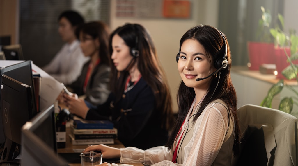 Profissional de atendimento sorrindo usando headset diante do computador