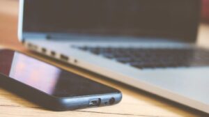 Smartphone e laptop sobre uma mesa, representando o trabalho entre dispositivos