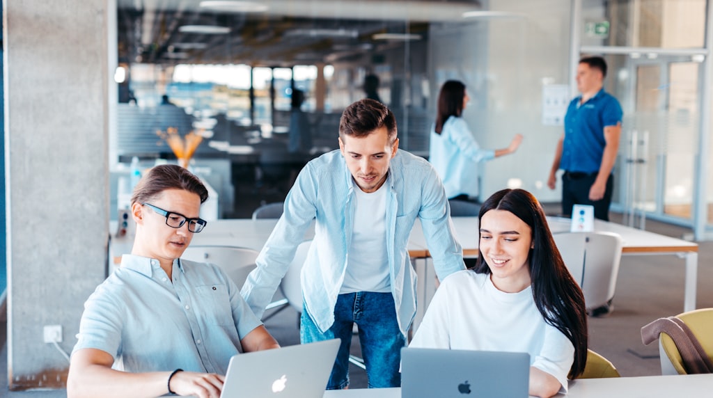 Equipe de marketing e vendas trabalhando com laptops ao redor de uma mesa