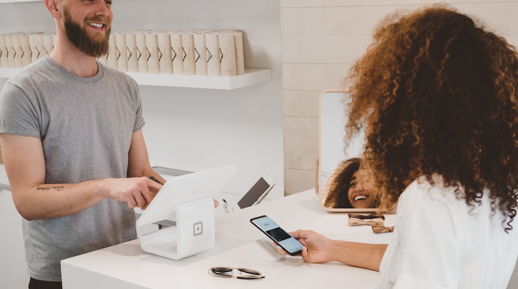Atendente sorrindo para cliente em um balcao de atendimento