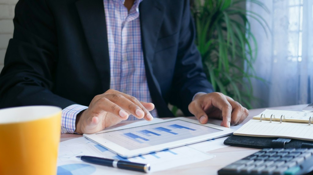 Profissional conferindo relatorios impressos com graficos sobre a mesa de trabalho