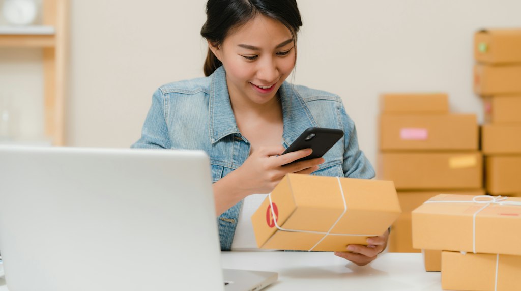 Avaliações de produto no e-commerce: consumidora confere pacote ao lado do notebook