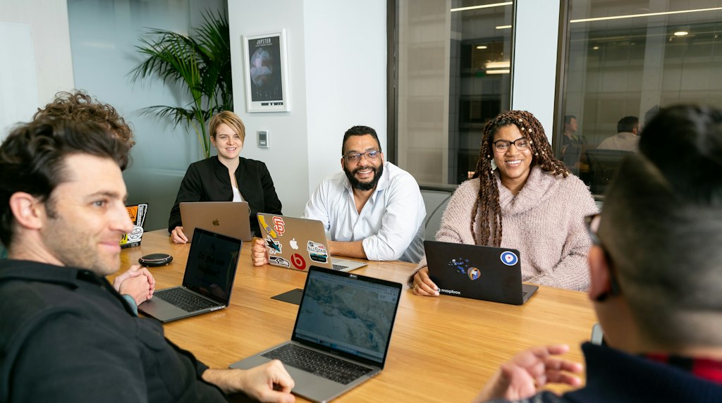 Quatro profissionais com notebooks em uma reuniao de trabalho