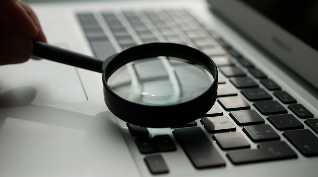 Lupa apoiada sobre um notebook, representando a busca online