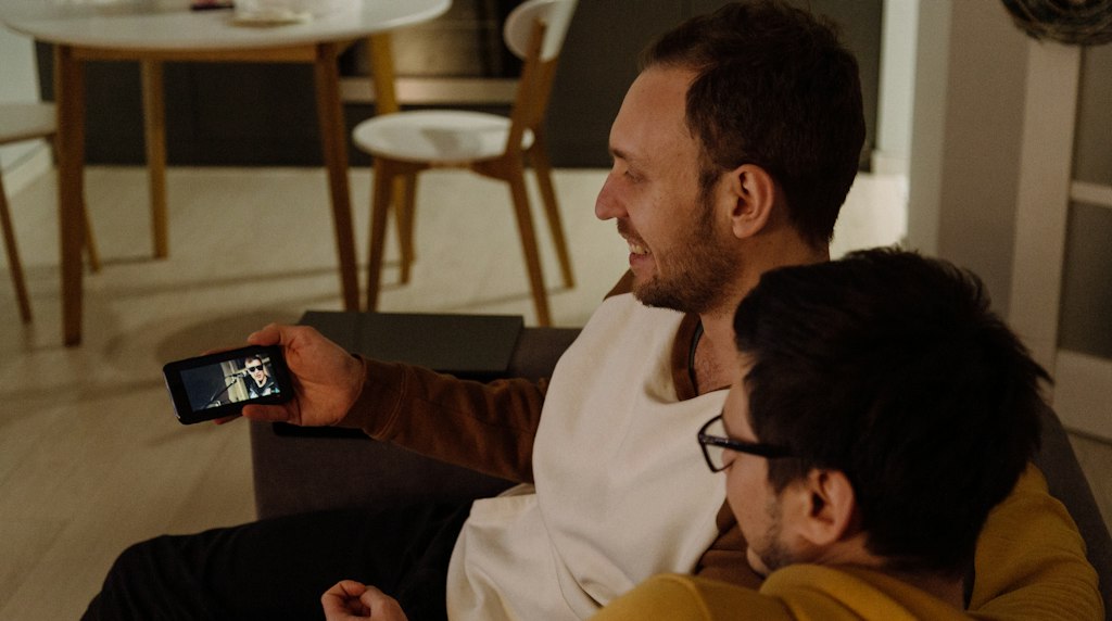 Duas pessoas sentadas assistindo a um video pelo smartphone