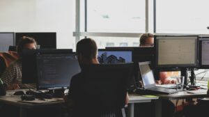 Pessoas sentadas em frente ao monitor do computador
