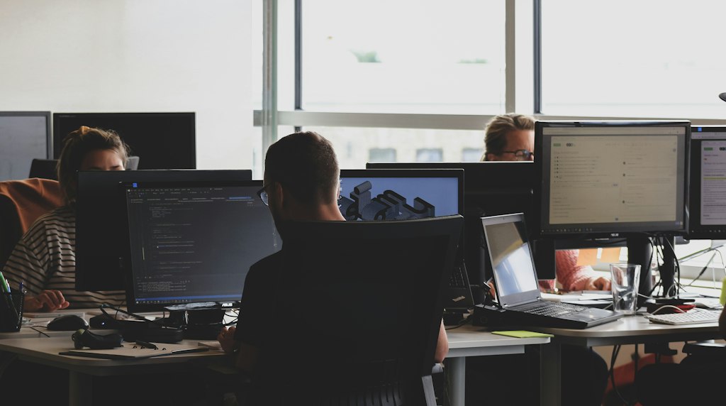 Pessoas sentadas em frente ao monitor do computador