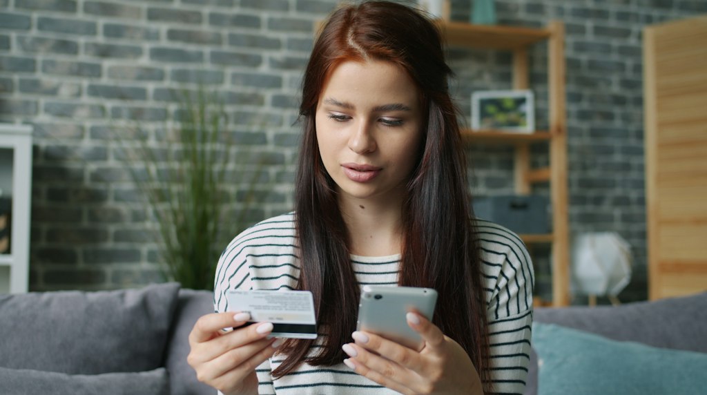 Pessoa segurando cartao de credito e smartphone para compras online