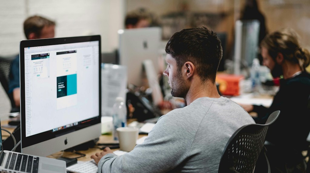 Profissional de marketing analisando campanhas em um computador de mesa em uma agencia