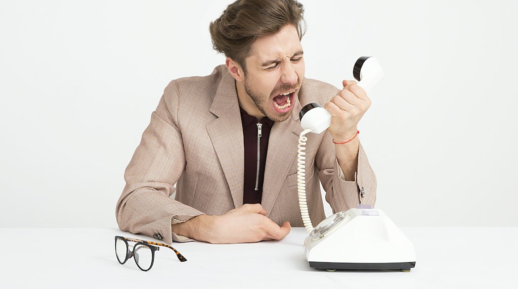 Homem gritando ao telefone, representando a perda de paciência do cliente com o atendimento automatizado