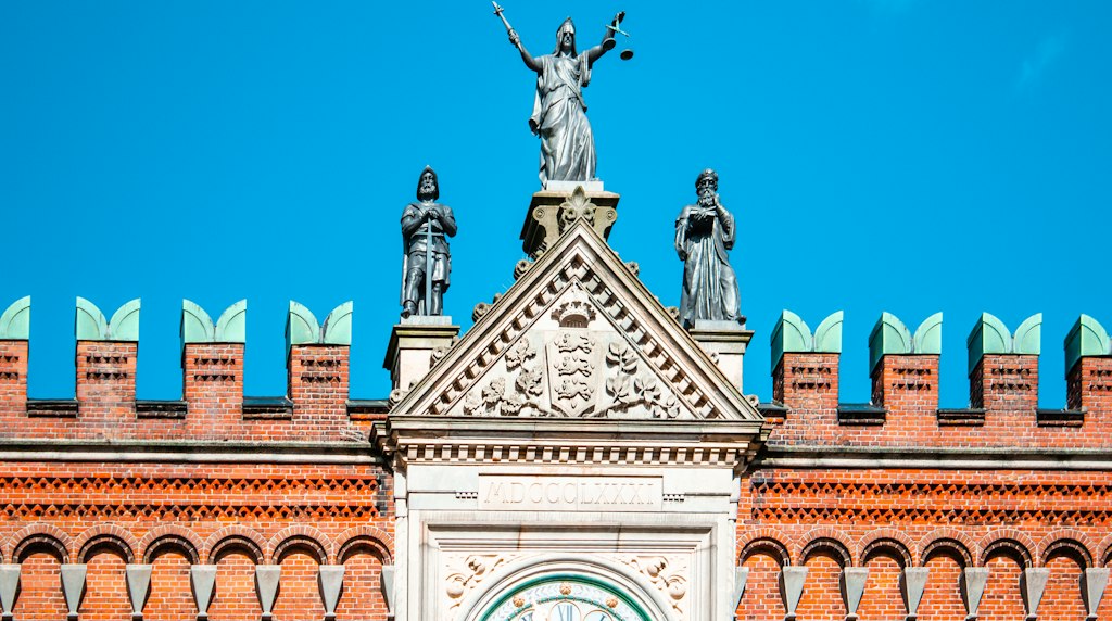 Estátua da senhora justiça no topo de um edifício com céu azul