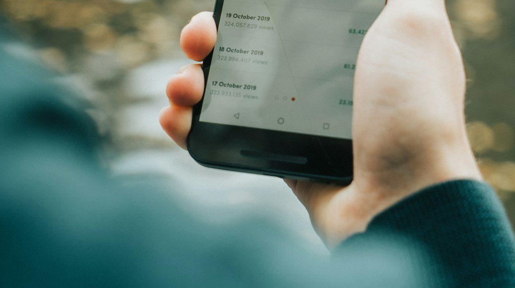 Pessoa segurando um smartphone com a mão, em uso cotidiano