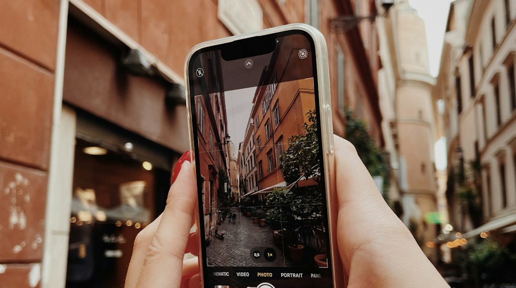 Mulher segurando um celular para fotografar uma rua da cidade