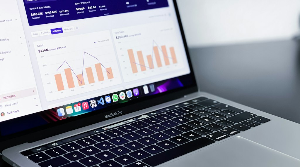 Mesa de trabalho com notebook exibindo gráficos de desempenho de uma loja virtual