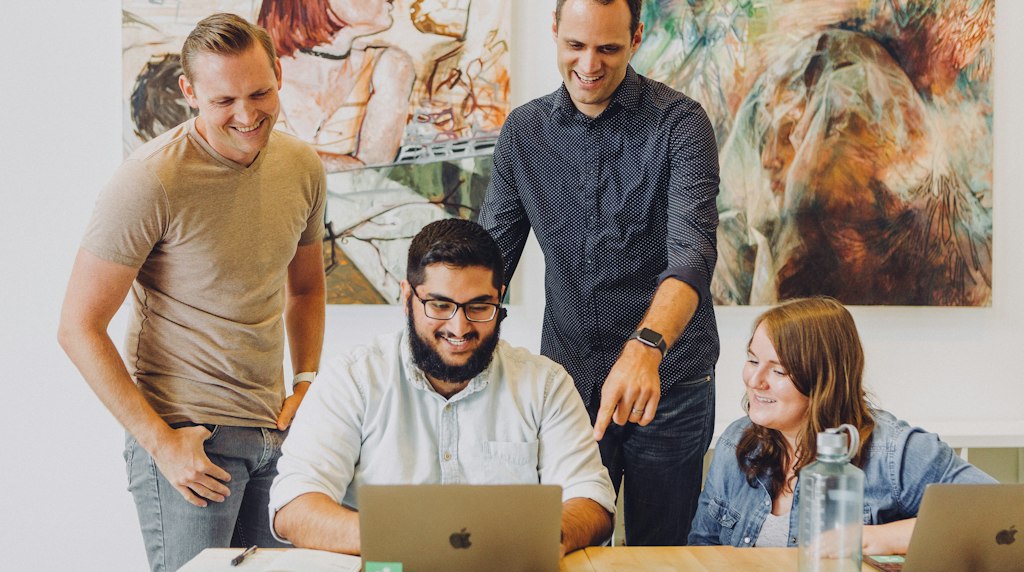 Colegas de trabalho reunidos em torno de um laptop