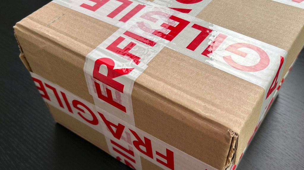 Caixa de papelão selada com fita vermelha, pronta para envio de uma compra online