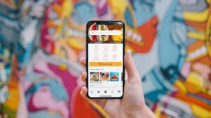 Pessoa segurando um iPhone branco com aplicativo de rede social aberto