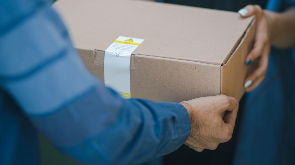 Entregador entregando uma caixa de papelão a um cliente