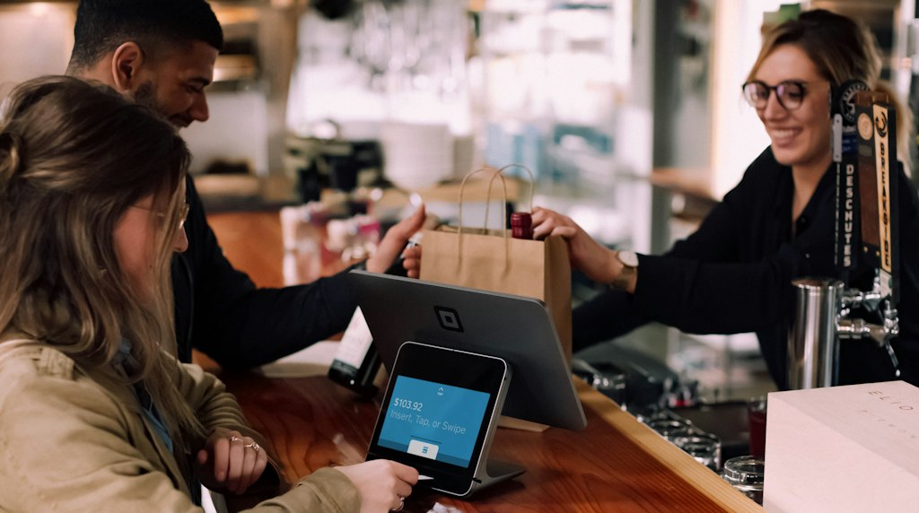 Pessoas usando dispositivos digitais para comprar em uma loja