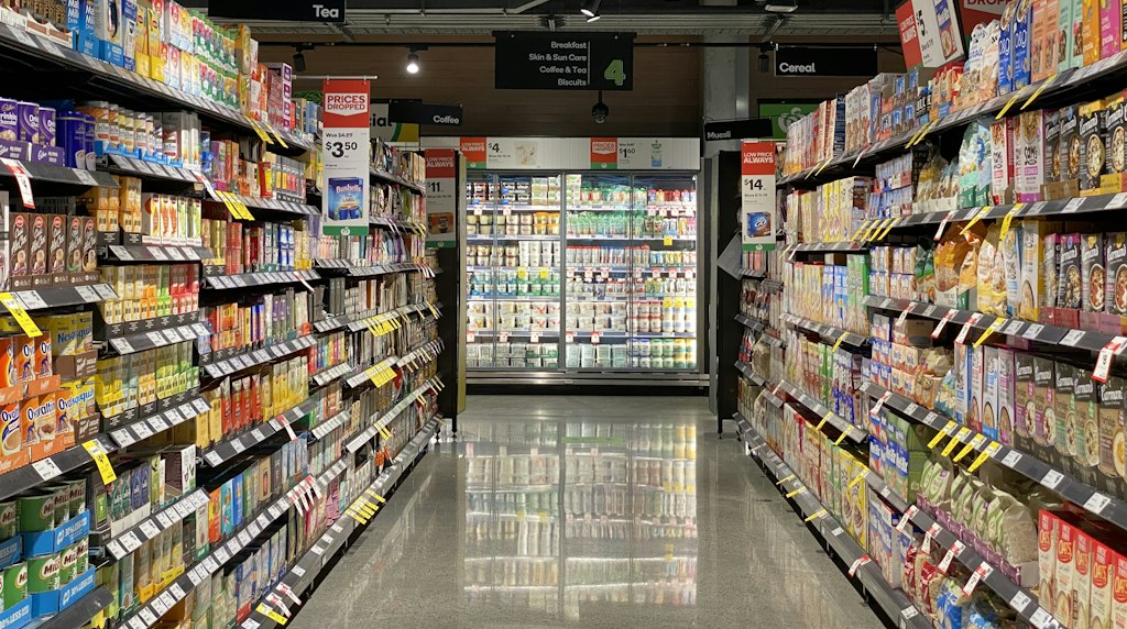 Corredor de supermercado com prateleiras de produtos, representando o varejo e a mídia de varejo
